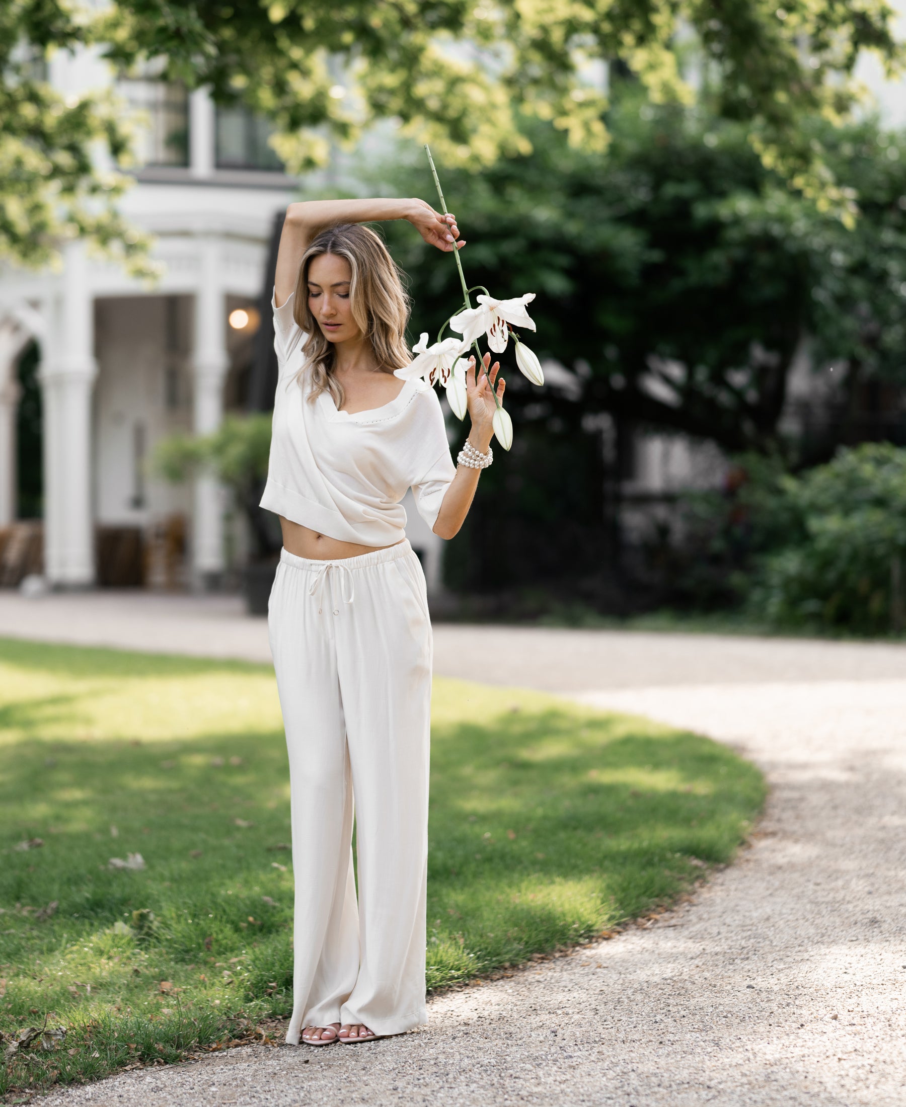 Cream-colored LA LYNETTE trousers by PLEIN PUBLIQUE shown outdoors.