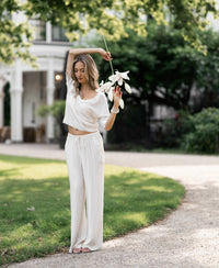 Cream-colored LA LYNETTE trousers by PLEIN PUBLIQUE shown outdoors.