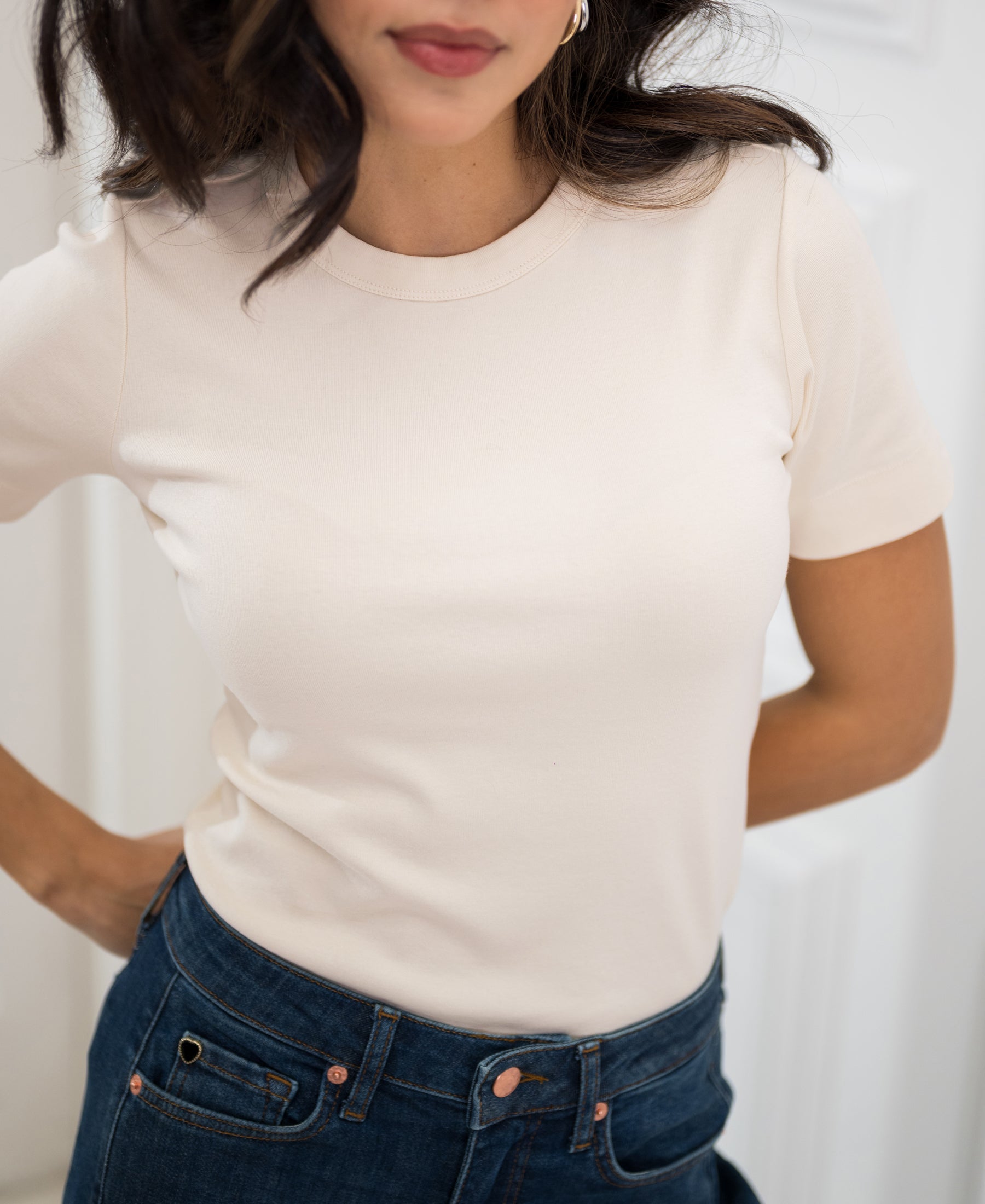 Woman wearing a luxe, soft butter-yellow LA MASSY T-shirt by PLEIN PUBLIQUE, standing indoors.