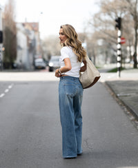 Light stone wide leg jeans with a relaxed fit, shown on a woman.