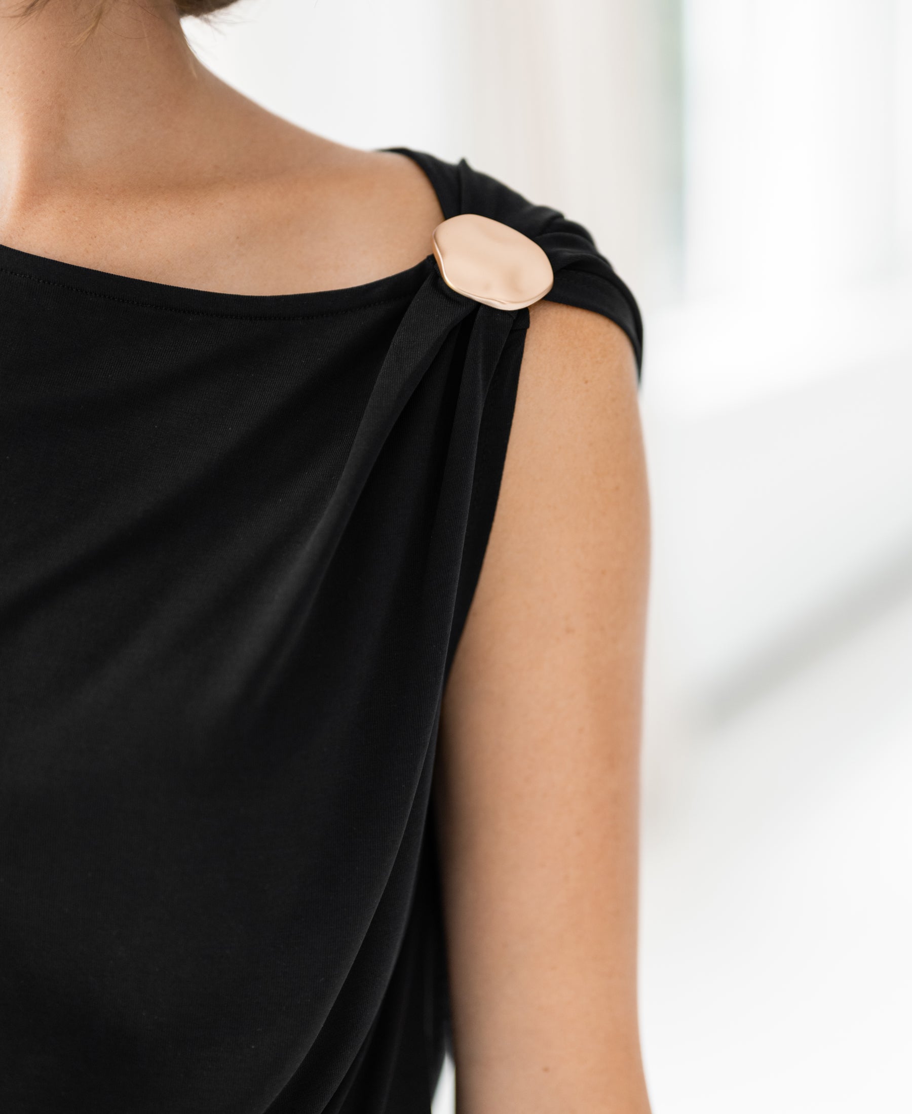 Black asymmetric stretch top with gold shoulder clasp by PLEIN PUBLIQUE.