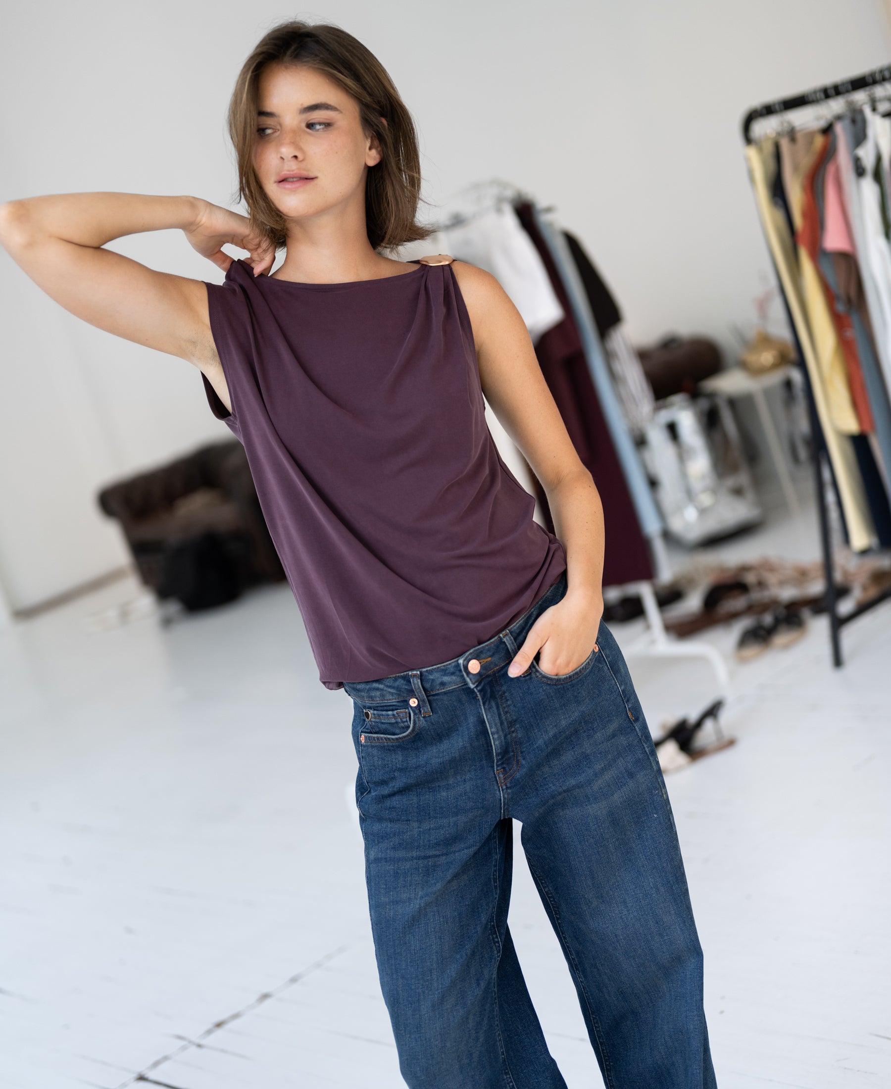 Woman wears the LA MAYA Wine top with clasp by PLEIN PUBLIQUE, shown in a bright room.