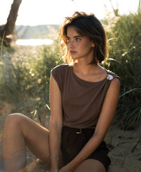 Brown LA MAYA top with buckle detail from PLEIN PUBLIQUE shown outdoors.