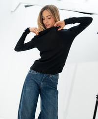 Black Luxe merino shirt in a relaxed fit, shown indoors with the model gently pulling at the collar.