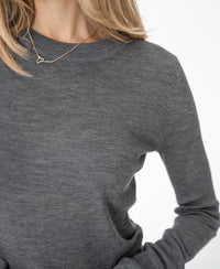 Woman wearing a grey PLEIN PUBLIQUE merino wool shirt, shown neck to waist.
