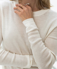 A person wears an ivory Luxe merino undershirt from PLEIN PUBLIQUE.