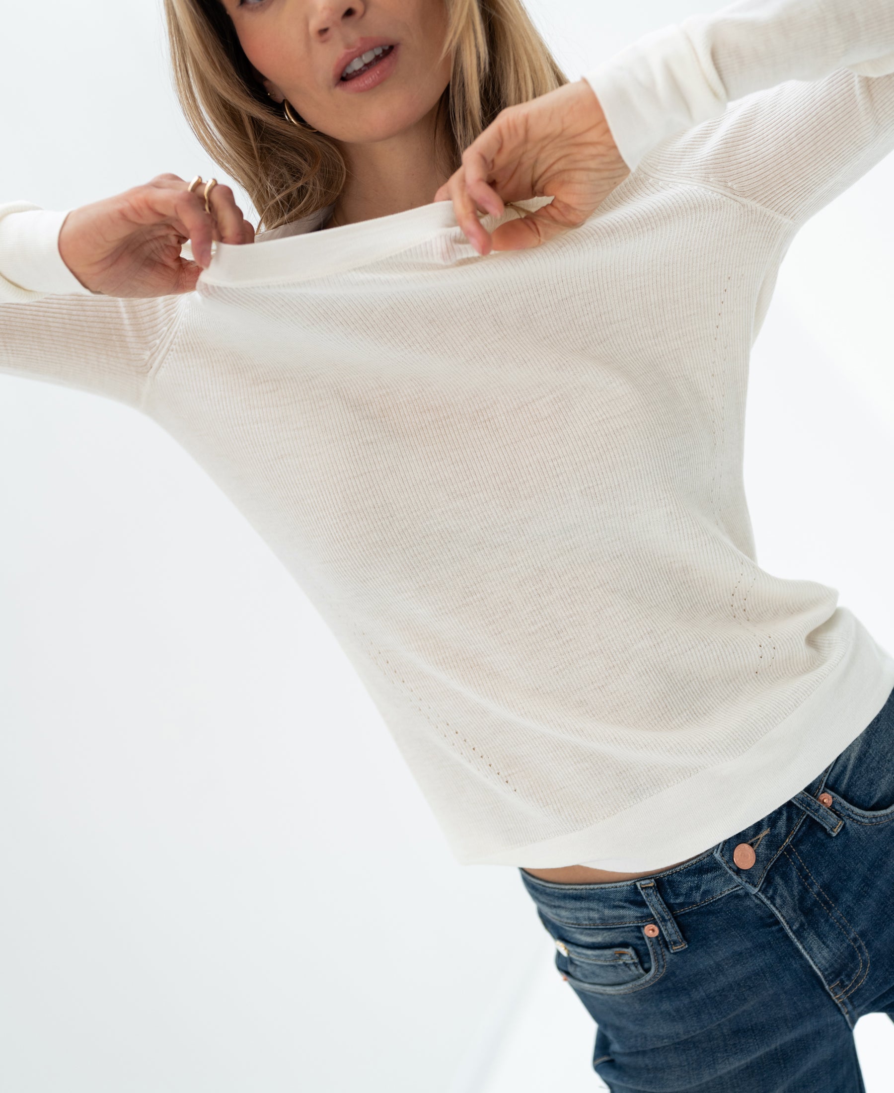 Ivory merino wool undershirt in a luxe style, shown being lifted slightly against a bright backdrop.