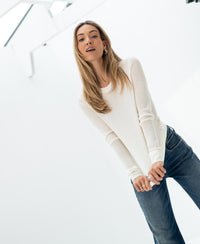 Ivory merino wool long-sleeve undershirt in a bright, modern white space.