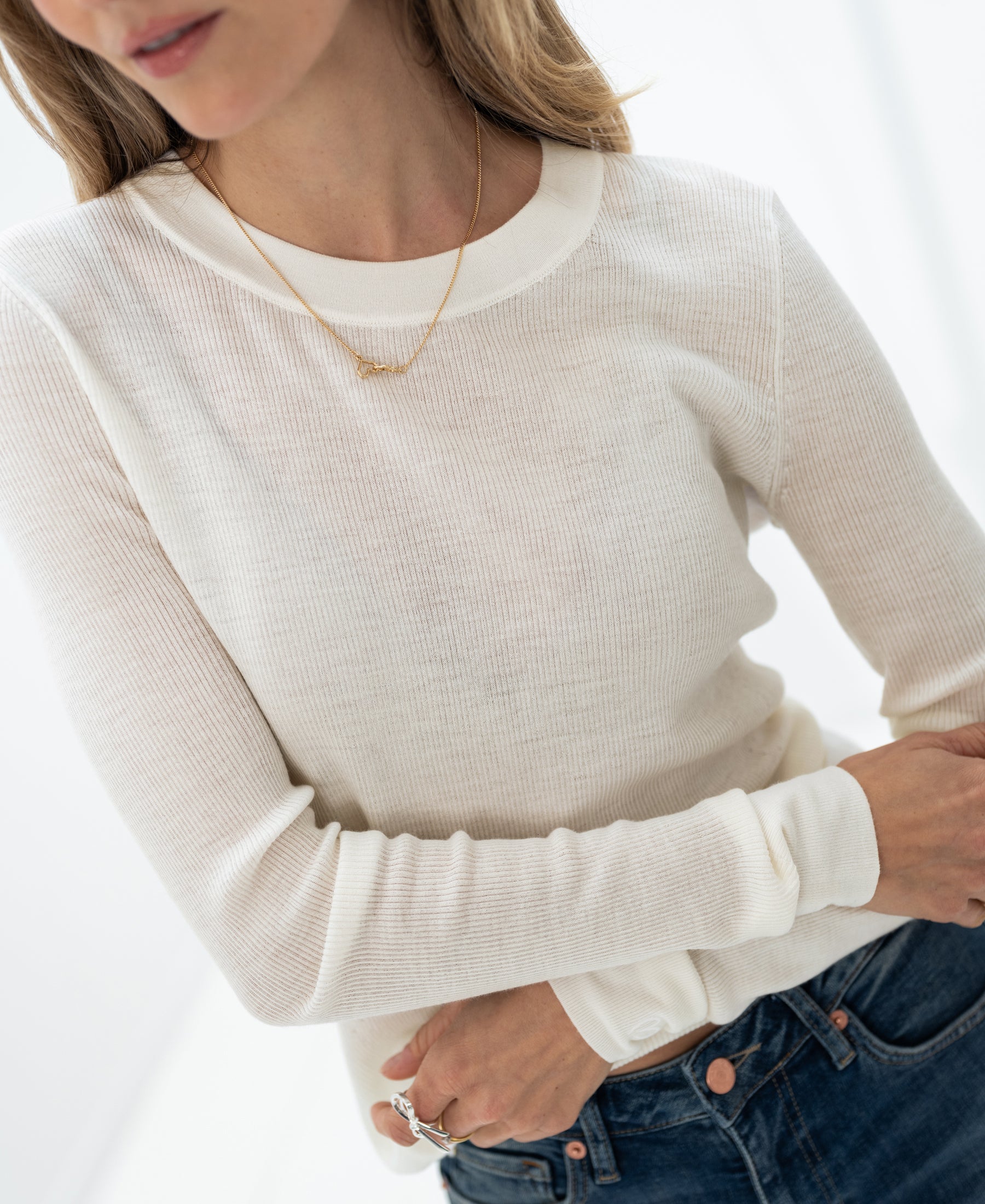 Woman wearing an ivory long-sleeve merino wool undershirt. Arms are folded.