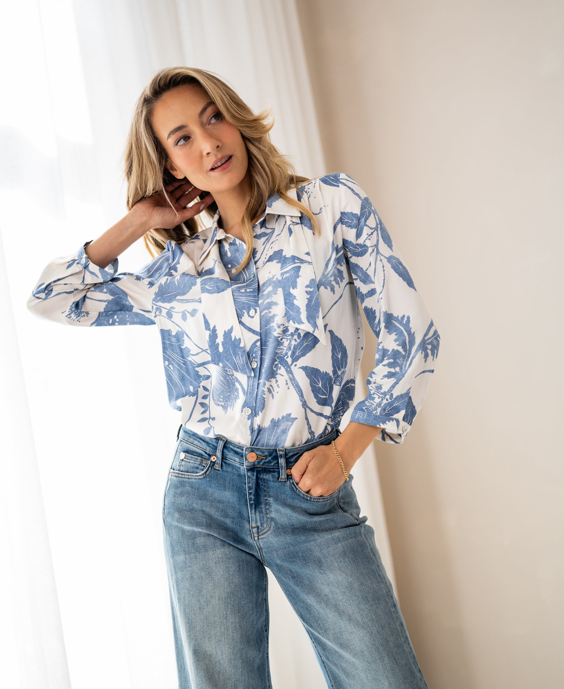 Woman wears PLEIN PUBLIQUE LA MINOU blouse with bow detail and floral print in size XL, posing indoors.