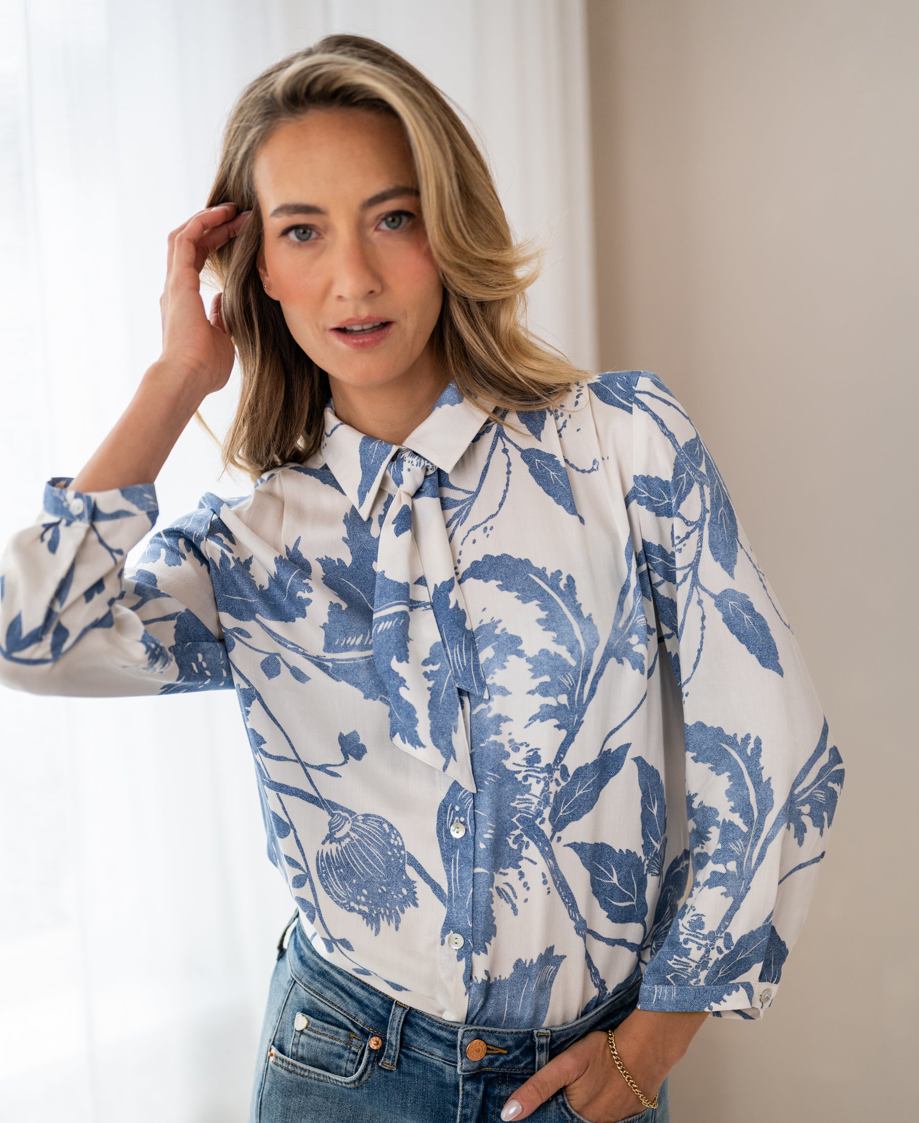 Woman wearing XL LA MINOU floral print blouse with tie detail by PLEIN PUBLIQUE.