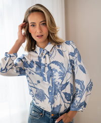 Woman wearing XL LA MINOU floral print blouse with tie detail by PLEIN PUBLIQUE.