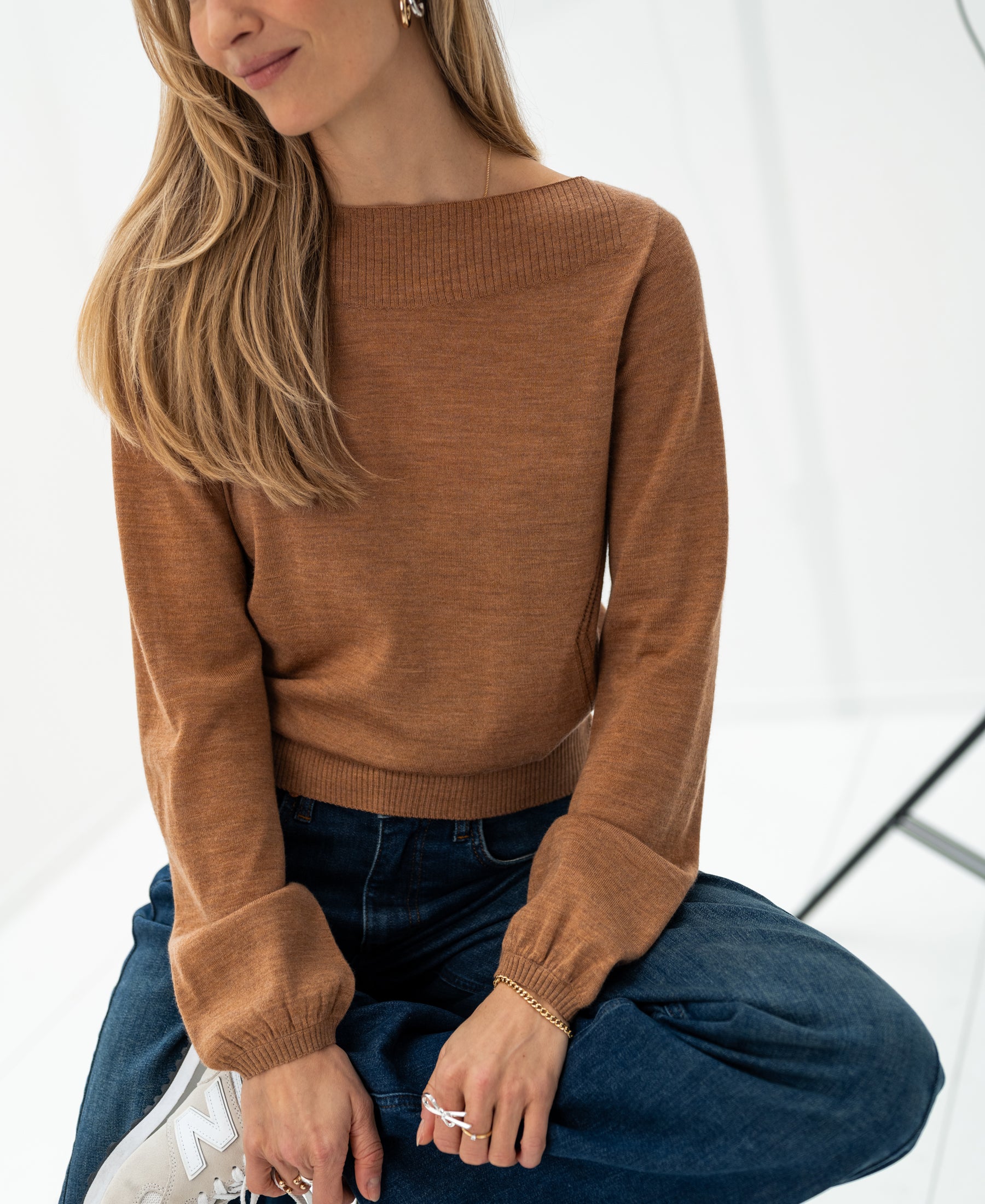 Woman wears the PLEIN PUBLIQUE LA MUSE boat neck sweater in Chai tea color.