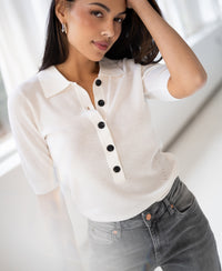 Woman wearing an ivory Merino wool polo sweater by PLEIN PUBLIQUE, posing indoors and looking at the camera.