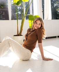 Camel-colored merino wool polo shirt shown indoors.