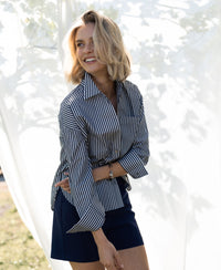 Striped white and anthracite blouse from LA PASCALLE, shown outdoors with sunlight filtering through leaves.