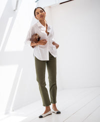 Woman wearing a white striped blouse by Plein Publique La Pascalle, standing in sunlight.