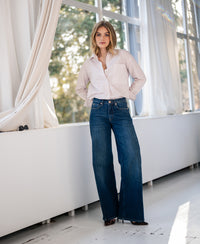 White and dark red striped LA PASCALLE blouse shown indoors with sunlight streaming through large windows.