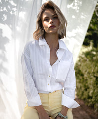 Woman wearing a white striped blouse by La Pascalle, pictured outdoors.