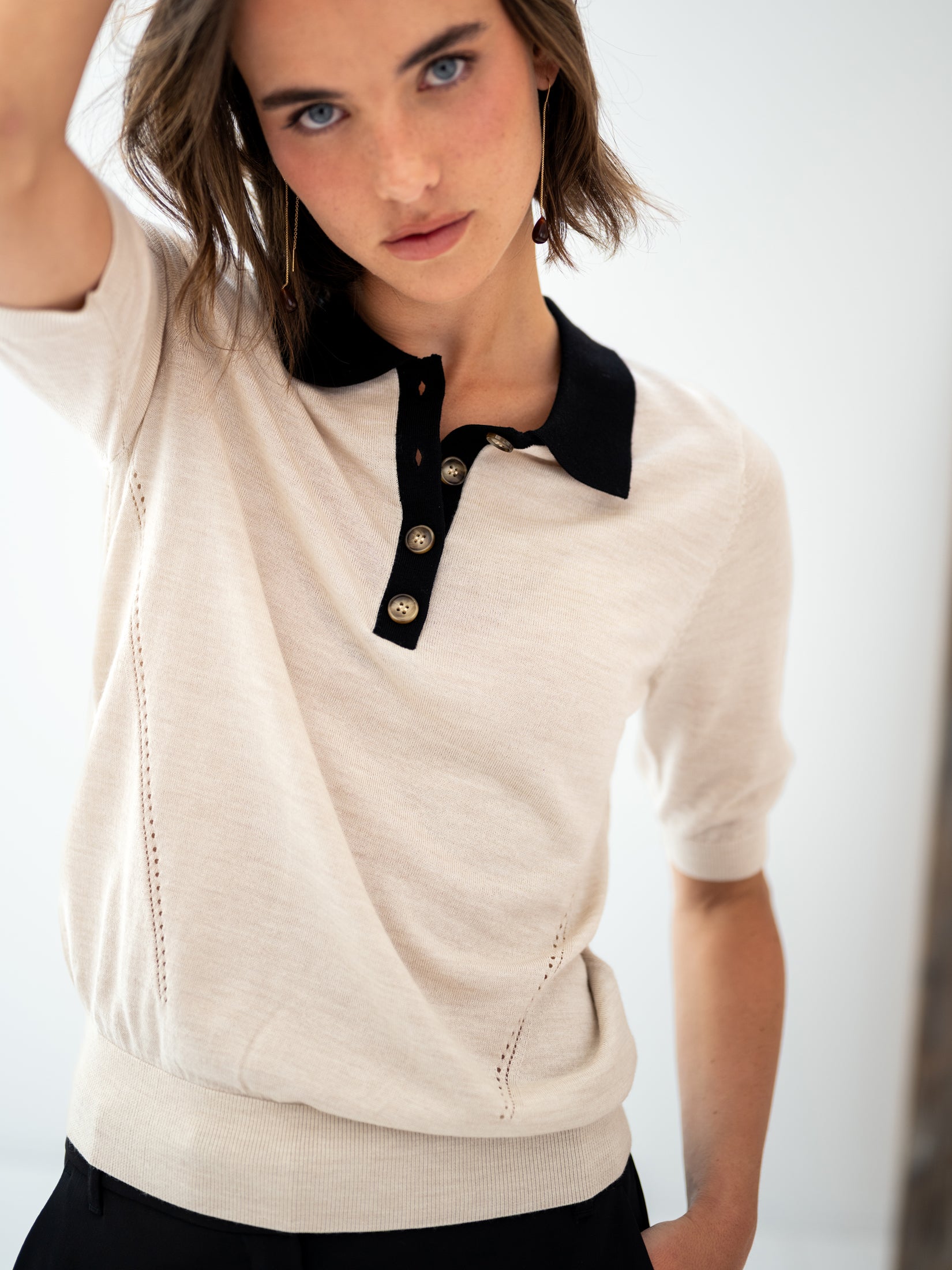 Merino wool-silk polo shirt in sand-black with black collar and buttons.