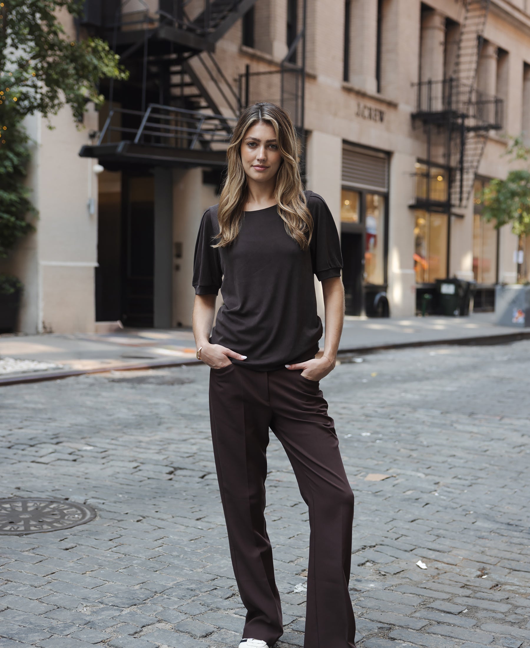 Chocolate brown ribbed T-shirt in a relaxed fit, shown outdoors with hands in pockets.