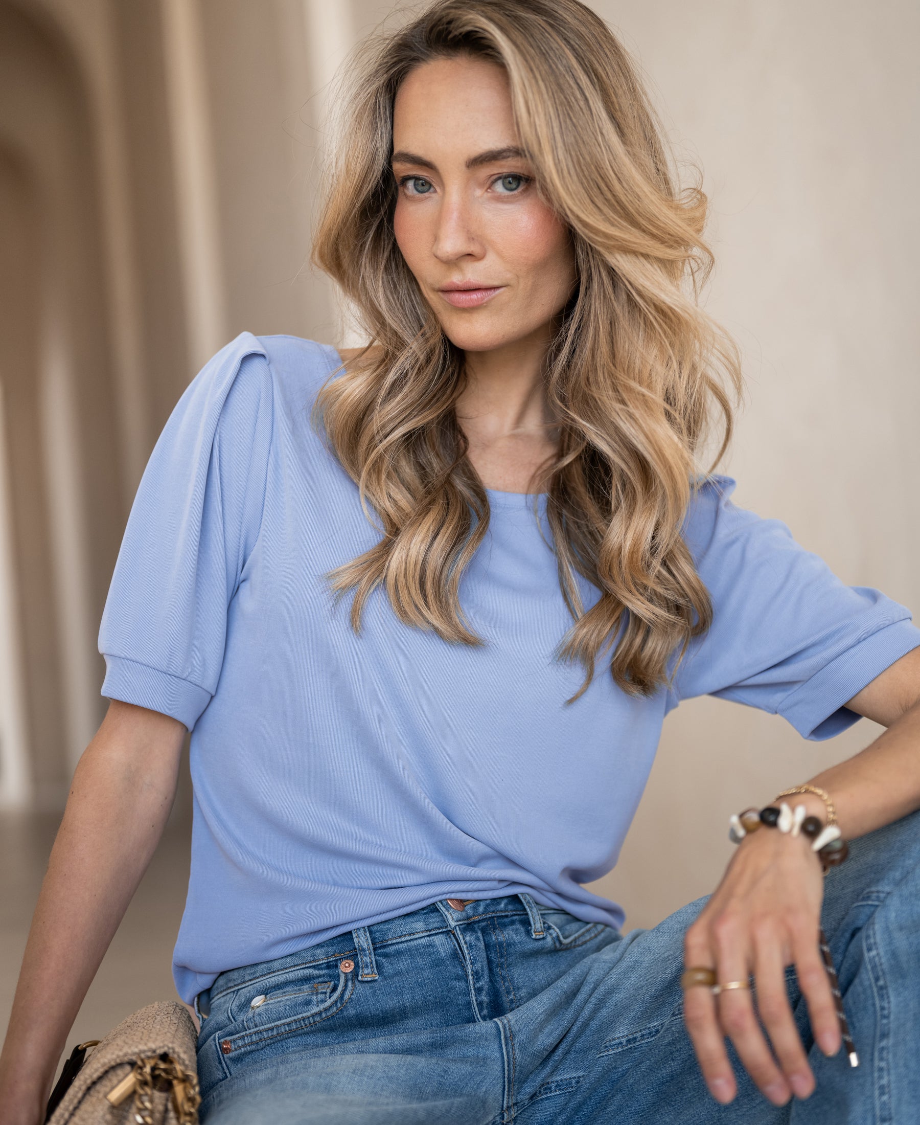Light blue ribbed T-shirt shown indoors, worn by a woman looking confidently at the camera.