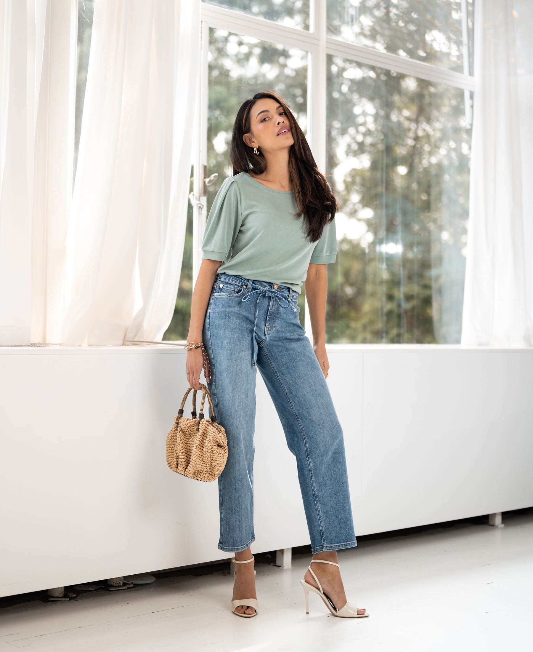 Woman indoors by windows wears a light green ribbed T-shirt from PLEIN PUBLIQUE.