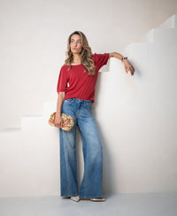 Woman wearing LA PHILEINE Rib T-shirt in red by PLEIN PUBLIQUE, standing by white stairs.