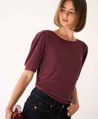Woman wearing a ribbed burgundy T-shirt by PLEIN PUBLIQUE, looking left.