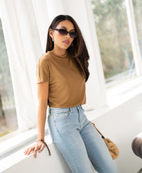 Yellow ribbed collared top by Plein Publique, LA PIERRE style, shown on a woman standing by a window.