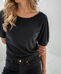 Charcoal rib T-shirt, named The Philine, by Plein Publique. Model wears it with hands behind her back.