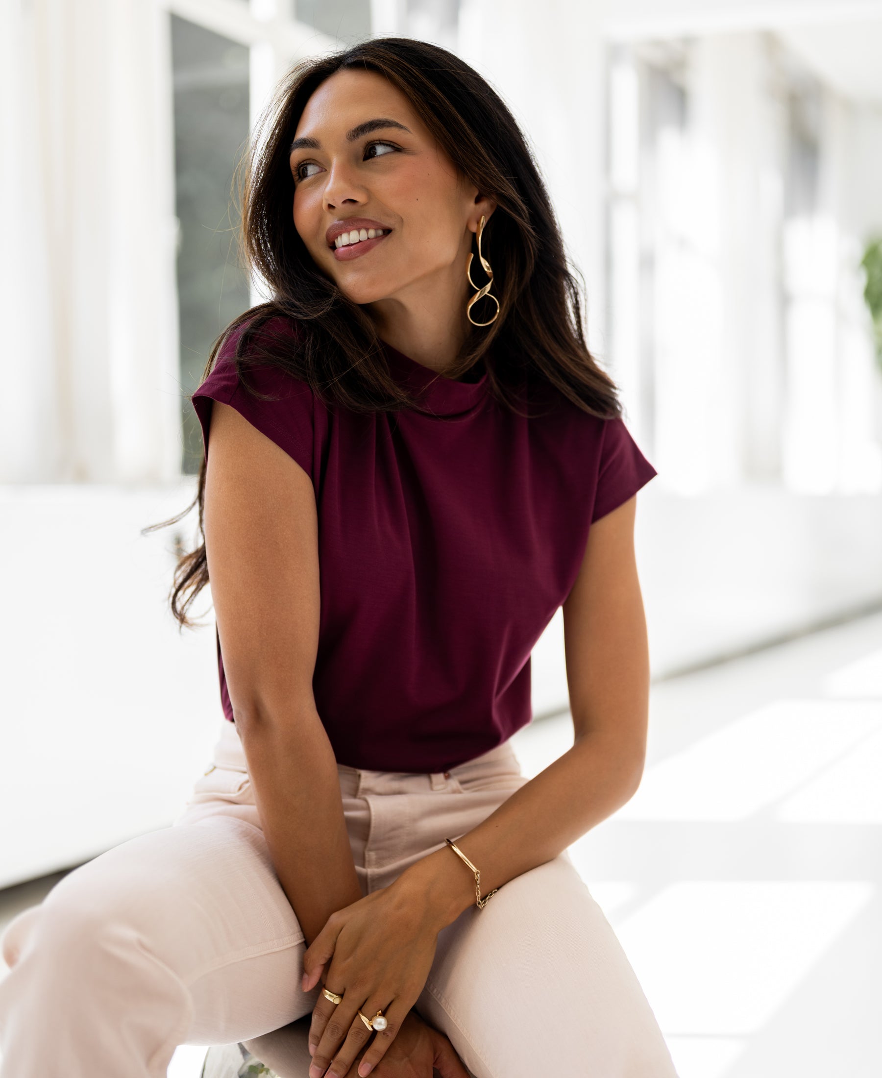 Woman wearing a burgundy PLEIN PUBLIQUE Travel collar top, LA ROMY, shown in natural light.