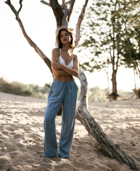 Striped linen-blend trousers in jeans blue on sandy ground in sunlight.