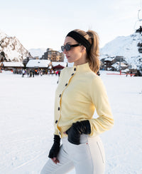 Soft yellow PLEIN PUBLIQUE merino wool turtleneck vest shown on a snowy ski slope.