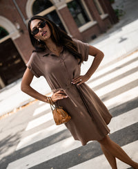 Woman wearing mocha mousse cupro dress stands at a crosswalk.
