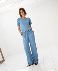 Light blue linen summer sweater shown in a bright, minimalist white room.