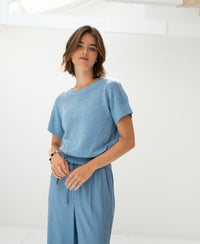 Light blue linen summer sweater shown against a bright minimal background.