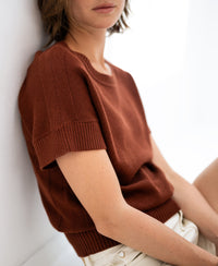 Linen summer sweater in Sierra color, shown on a woman seated and turned slightly away.