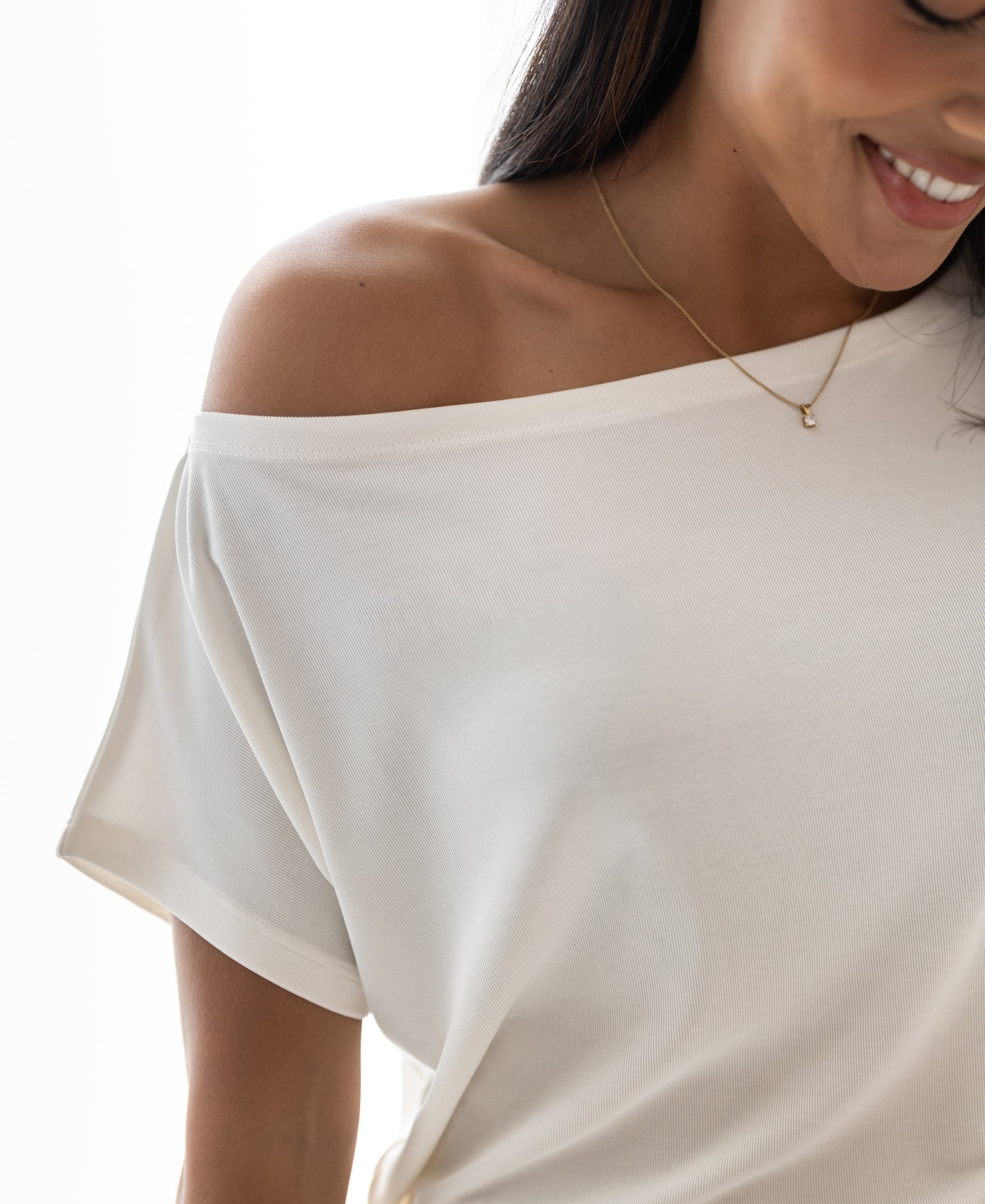 Woman wearing an ivory ribbed boat-neck T-shirt, face partly out of view.