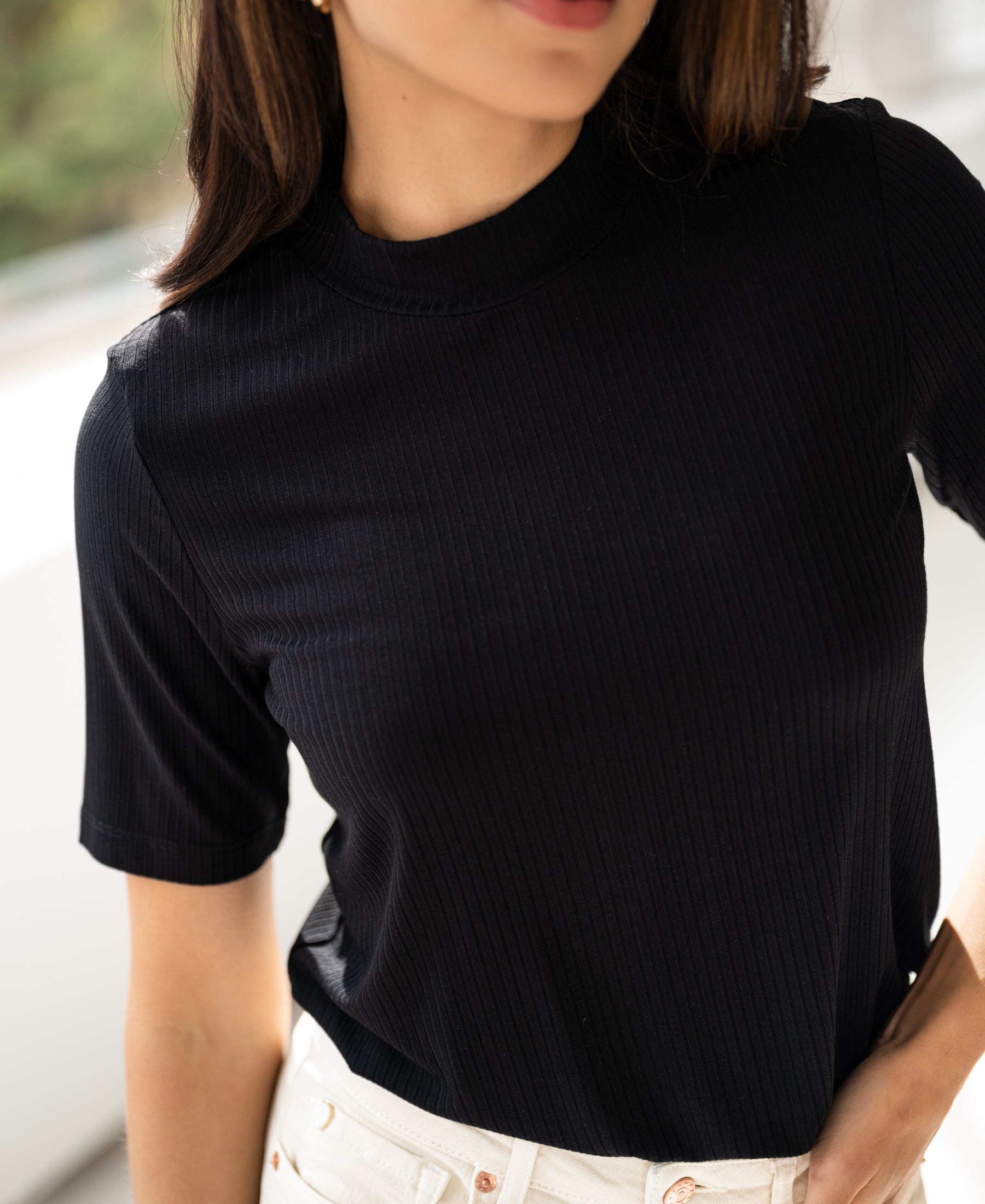 Black bamboo turtleneck top shown from shoulders to waist in natural light.