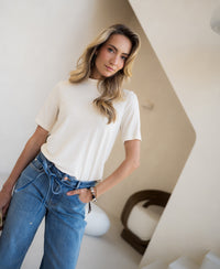 Cream bamboo long-sleeved top by PLEIN PUBLIQUE, shown in a modern minimalist room.