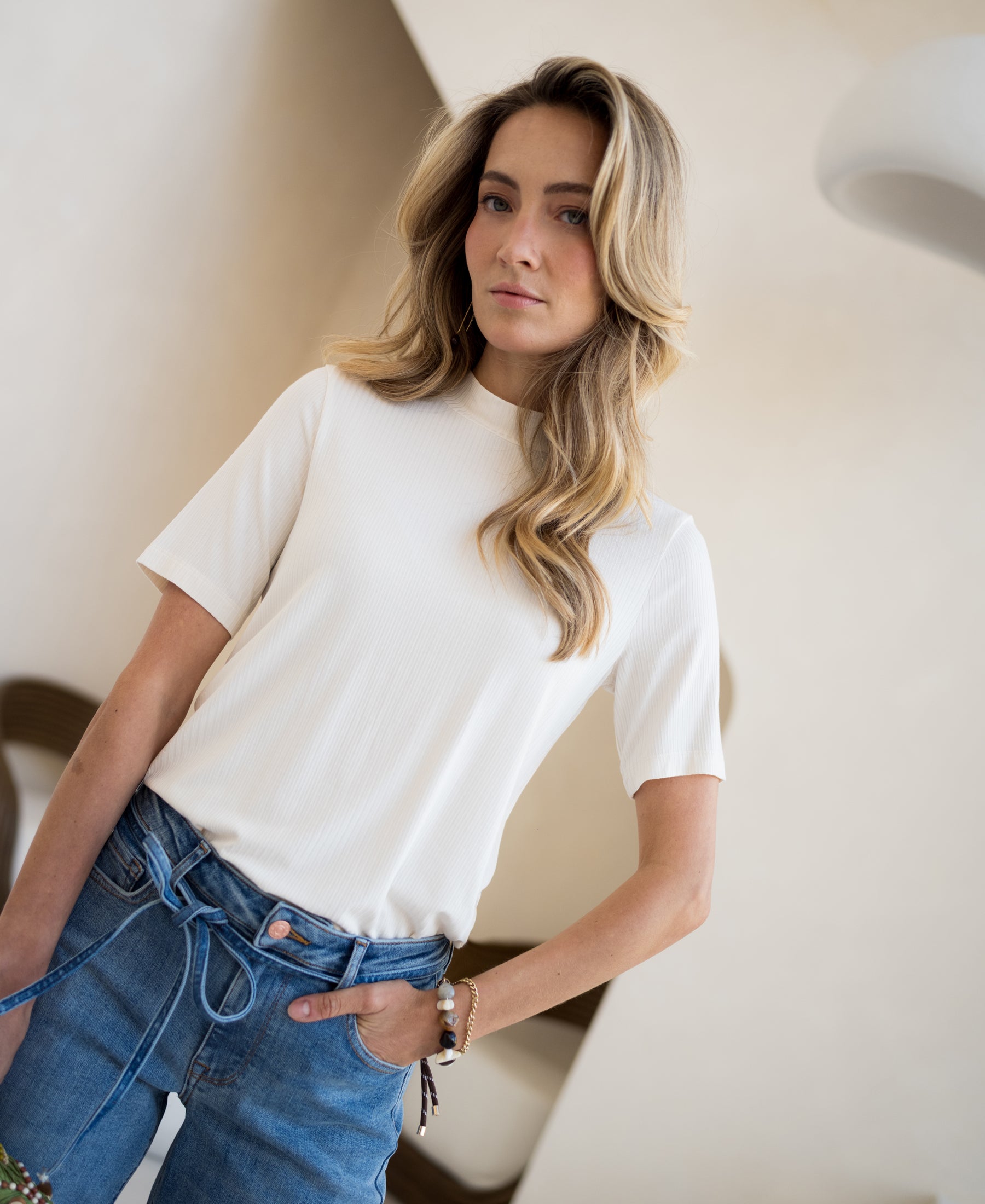 Cream bamboo turtleneck top LA SOMMET by PLEIN PUBLIQUE, worn by a woman with wavy blonde hair indoors.