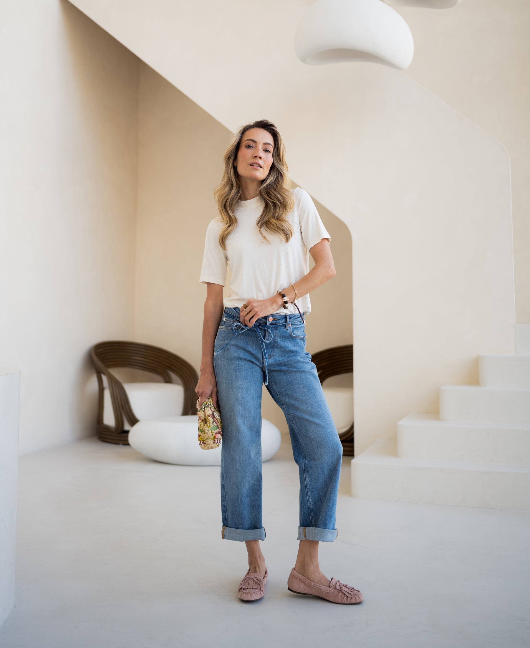 Woman wearing a cream bamboo top stands indoors near modern decor.
