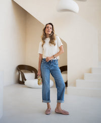 Woman wearing a cream bamboo top stands indoors near modern decor.