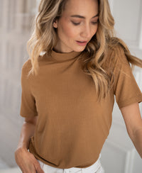 Ochre bamboo mock neck top in a long-sleeve style, shown on model looking down.