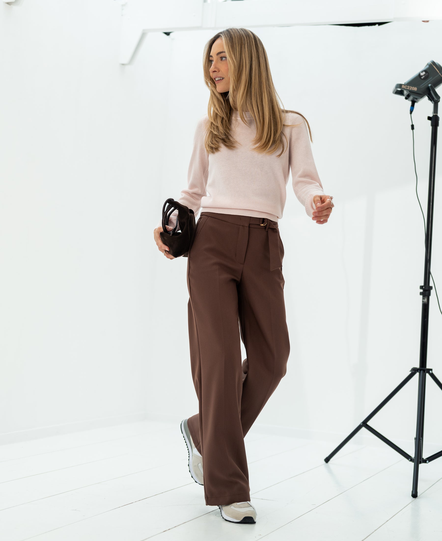 Woman wearing a blush pink merino blend sweater in a bright white studio.