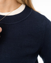 Close-up of a person wearing the PLEIN PUBLIQUE navy merino blend sweater.