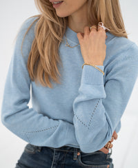Woman wearing a light blue Merino blend sweater by PLEIN PUBLIQUE.