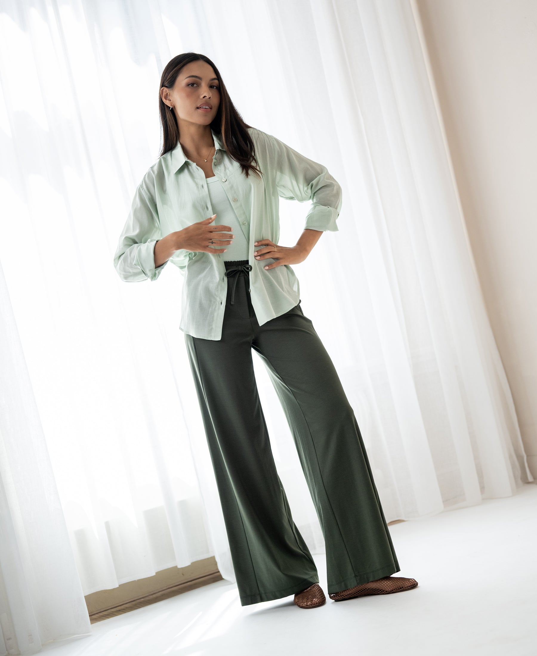 Woman poses indoors wearing a dark olive viscose mix PLEIN PUBLIQUE LA JULIA travel pant.