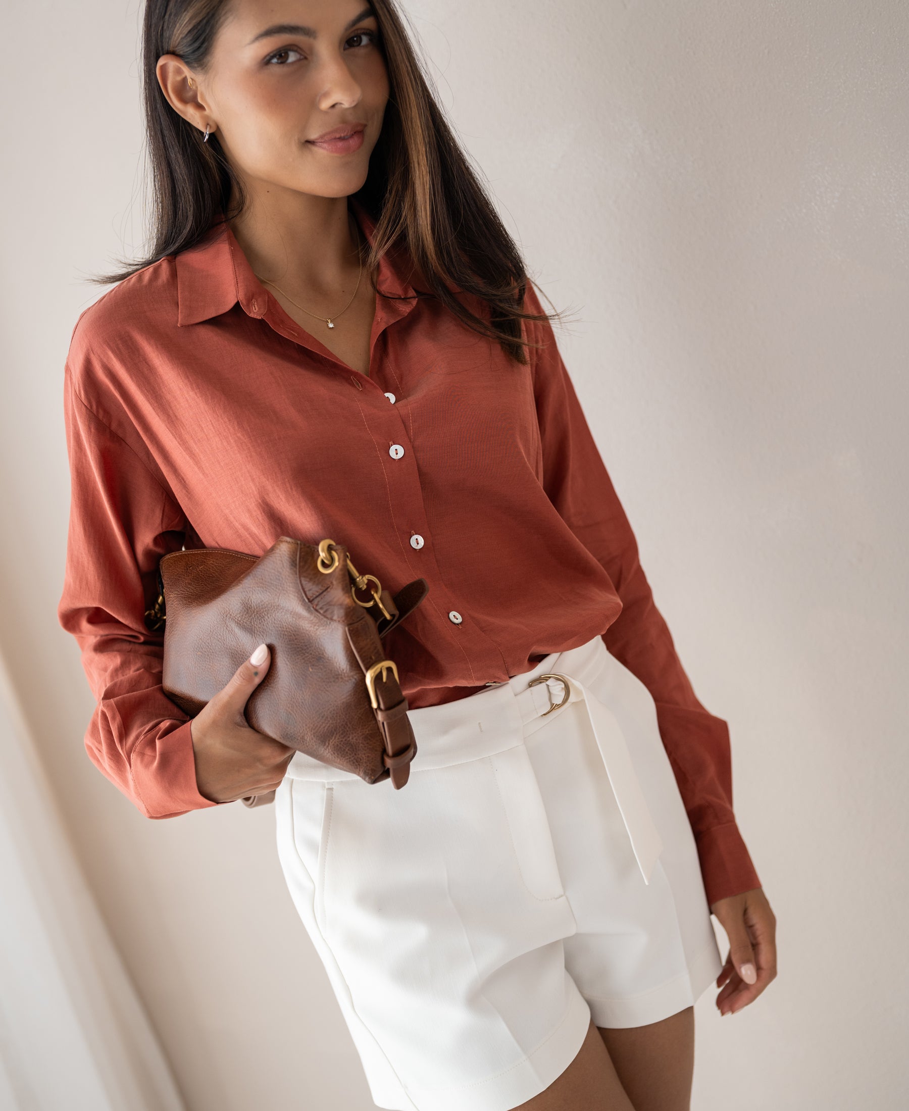 Woman wearing oversized Terra-colored LA SOYEUSE blouse by PLEIN PUBLIQUE, standing against a light wall.